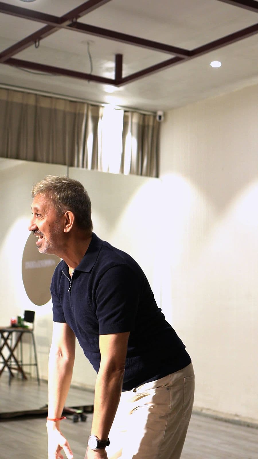 Neeraj Kabi leaning forward, smiling, as he watches the room