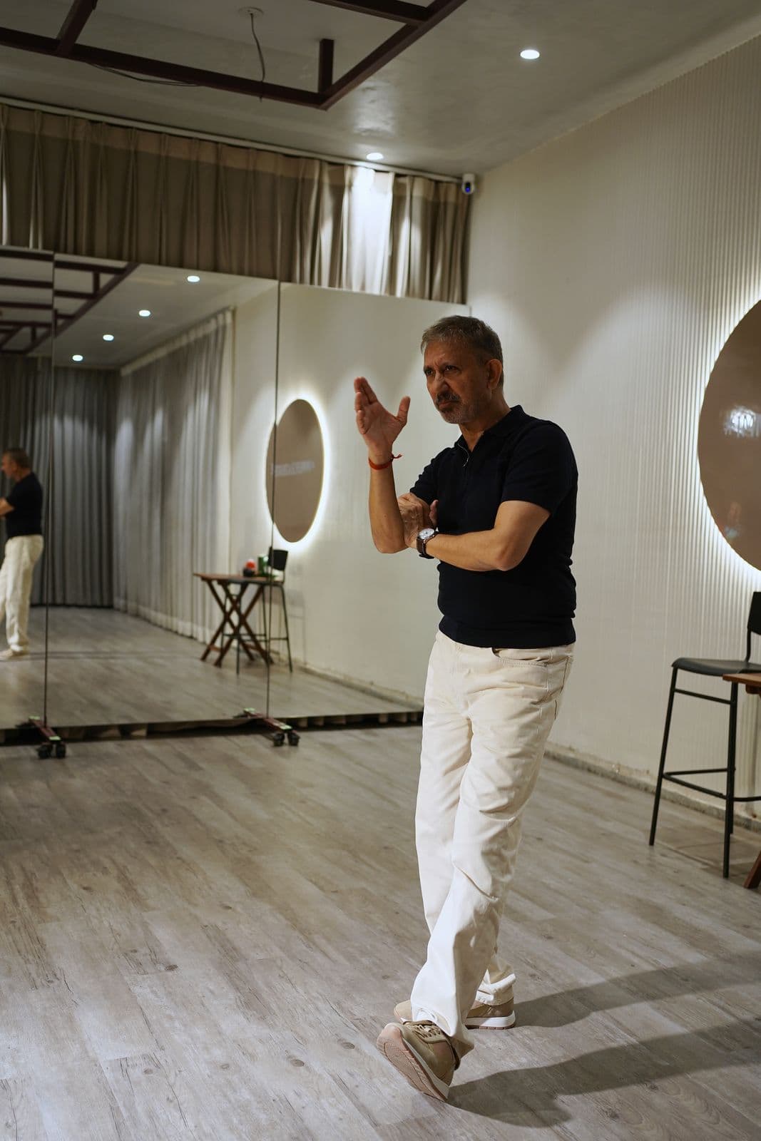 Neeraj Kabi mid-demonstration, one hand raised, on the studio floor