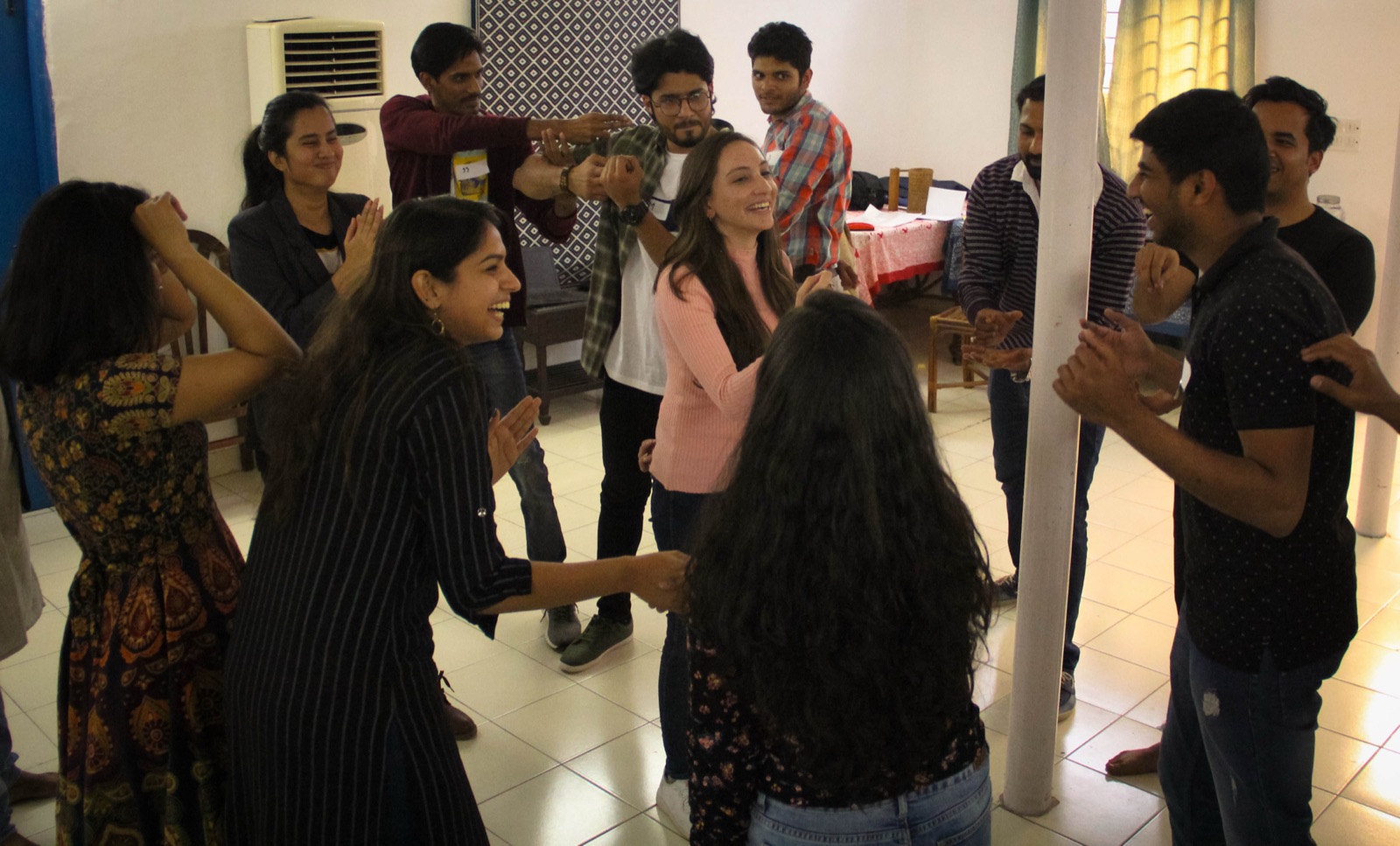 A workshop group mid-exercise, laughing and moving together in a circle