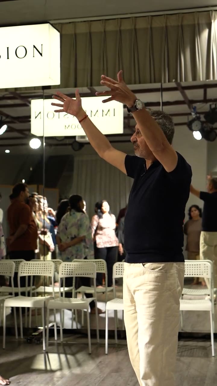 Neeraj Kabi raises both arms and holds them as the room follows, in The Actor's Power